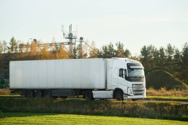 Beyaz modern yarı kamyonet, güneşli bir günde mal dağıtıyor.