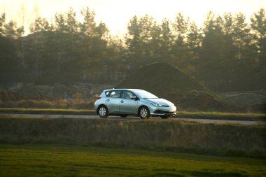 Küçük bir hatchback huzurlu kırsaldan geçiyor.