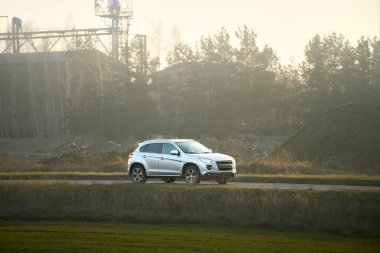 Sonbahar manzarasında alacakaranlıkta gezinen bir SUV.