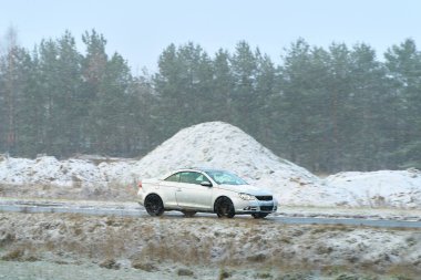 Kış yolunda giden küçük bir araba.