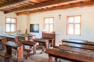 Ahşap masaları ve bankları olan antika bir sınıf.