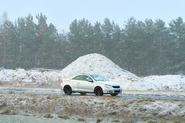 Kış yolunda giden küçük bir araba.