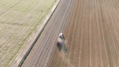 Tozlu tarlada çalışan kırmızı traktör
