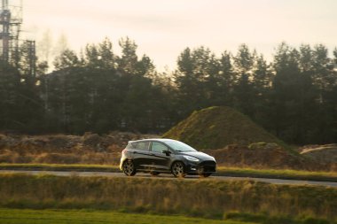 Çevre dostu araba, kır yolunda ilerliyor.