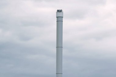 Bulutlu gökyüzünün ortasında uzun bir baca yığını