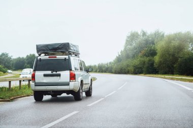 Çatı çadırı olan bir minivan kırsaldan geçiyor.