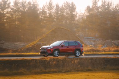 Kırsalda lüks bir araç sürüyor.