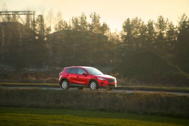 Akşam vakti kırsal yolda araba parlıyor.