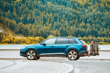 Manzaralı bir yolda bisiklet taşıyan mavi bir SUV