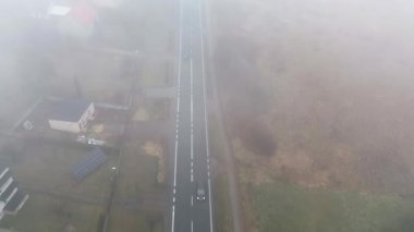 Banliyölerdeki puslu caddede gezinen arabanın insansız hava aracı görüntüleri.