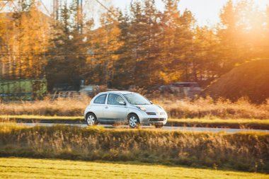 Akşamleyin kır yolundan geçen beyaz bir araç.
