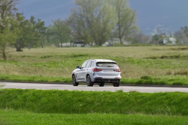 Lüks SUV bir kır yolunda ilerliyor.
