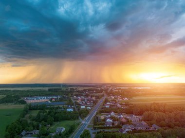 Fırtına bulutları ve gün batımı ışığıyla kırsal manzara