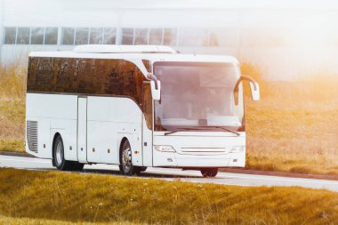 Modern beyaz otobüs sanayi bölgesi yakınlarındaki kırsal yolda seyahat ediyor.