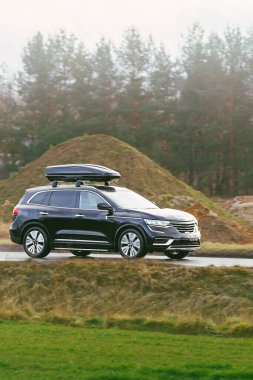 Çatı depolama kutusu olan araba doğada seyahat ediyor.