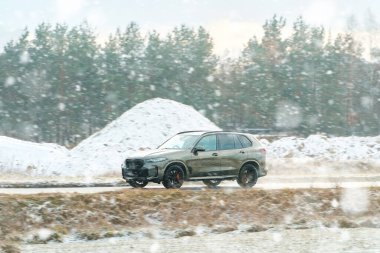 Karlı kırsal yolda SUV hareket halinde.