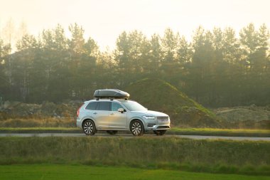 Çatı kutusu açık yolda giden bir SUV.