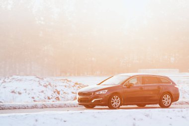 Gri araba karlı yolda gidiyor.