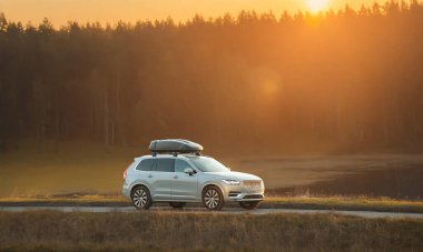 Kırsal yolda çatısı kargo kutusu olan bir SUV.