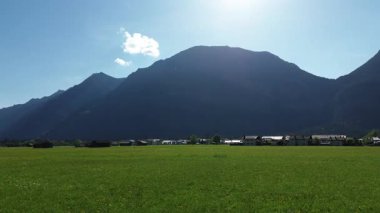 Kırmızı çatıları ve dağları olan yemyeşil bir kırsal.