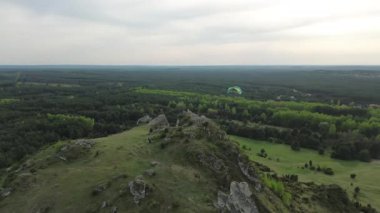 Yeşil orman manzarasının üzerindeki maceracı paraglider