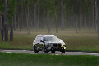 Arka planda manzaralı kırsal bir yolda giden şık siyah SUV.