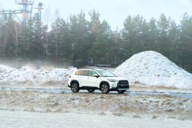 Karlı orman yolunda araç sürüyor.