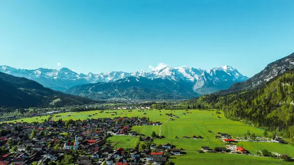 Yeşil manzaralı köyün üzerinde kar kaplı Alpler