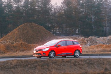 Hareket halindeyken güneş ışığını yansıtan parlak kırmızı bir araç