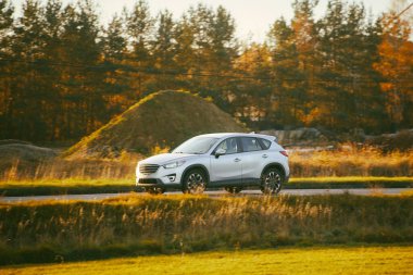 Şehir sınırına yakın beyaz araba sürüyor.