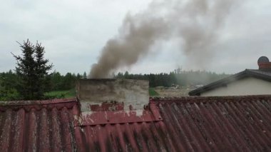 Evin bacasından siyah egzoz dumanı geliyor.