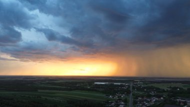 Kara fırtına bulutlarının yaklaştığı kırsal bölgede gün batımı