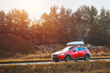 Kırsal yolda giden çatılı kargo kutusu olan bir araba.