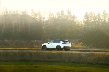 Güneşli bir kır yolunda giden SUV.