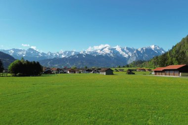 Karlı tepeleri olan yeşil dağlık arazi ve orman