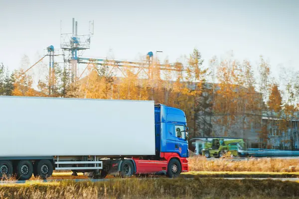 Kırsal yolda beyaz kamyon sürüyor.