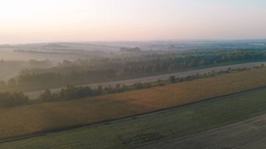 Güneşin doğuşu sisli tarlaları ve dağ yamaçlarını aydınlatıyor.