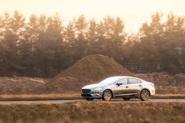 Yolda krom ayrıntı taşıyan parlak siyah bir sedan.