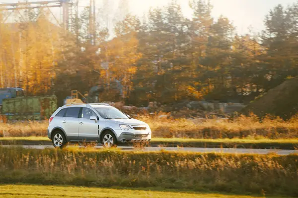 Kırsalda lüks bir araç sürüyor.