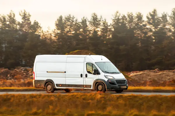 Beyaz minibüs doğada asfalt yolda ilerliyor.