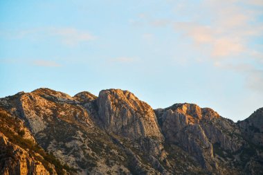 Kayalık dağ zirveleri açık mavi gökyüzüne uzanıyor