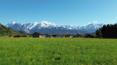 Karla kaplı dağ sırtına uzanan yeşil çayır.