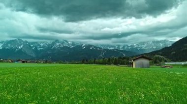 Alpleri ve dramatik bulutları olan yeşil çayır