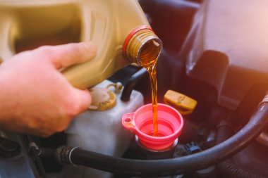 Otomatik tamirci araba motorunu yağ ile dolduruyor