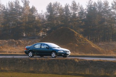 Parlak siyah sedan açık havada hareket ediyor.