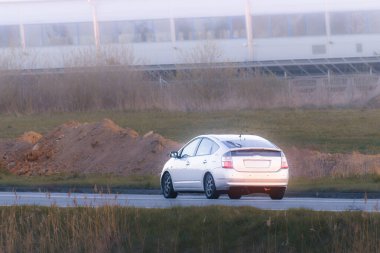 Elektrikli SUV boş köy yolunda ilerliyor.