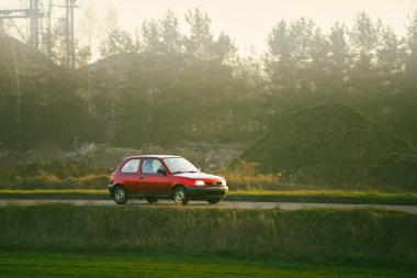 Kırsal bir yolda giden küçük bir hatchback arabası
