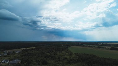 Fırtınalı bulutların altında uzanan yeşil alanlar