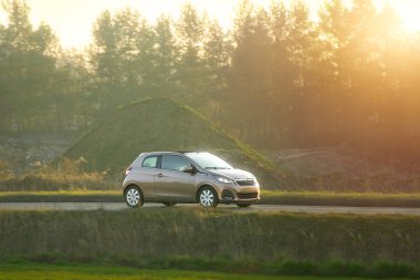 Küçük aile arabası kırsal yolda ilerliyor.