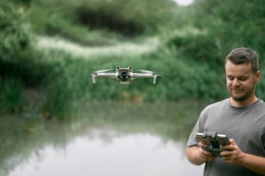 Gülümseyen adam deniz kenarında dron kullanıyor.